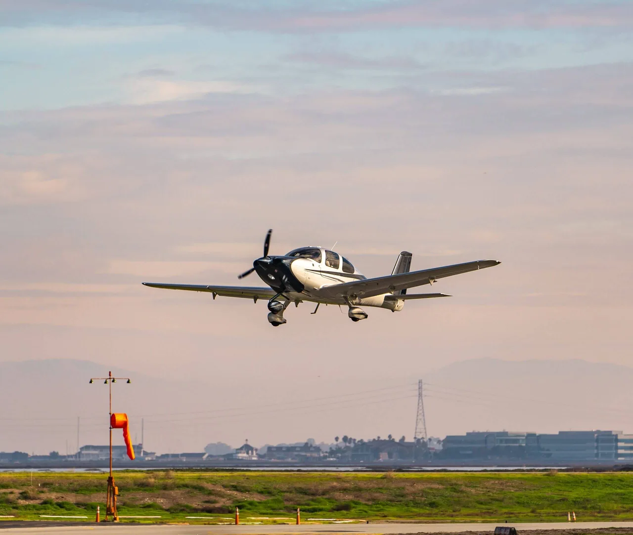 A Cirrus SR20 flying above an airfield