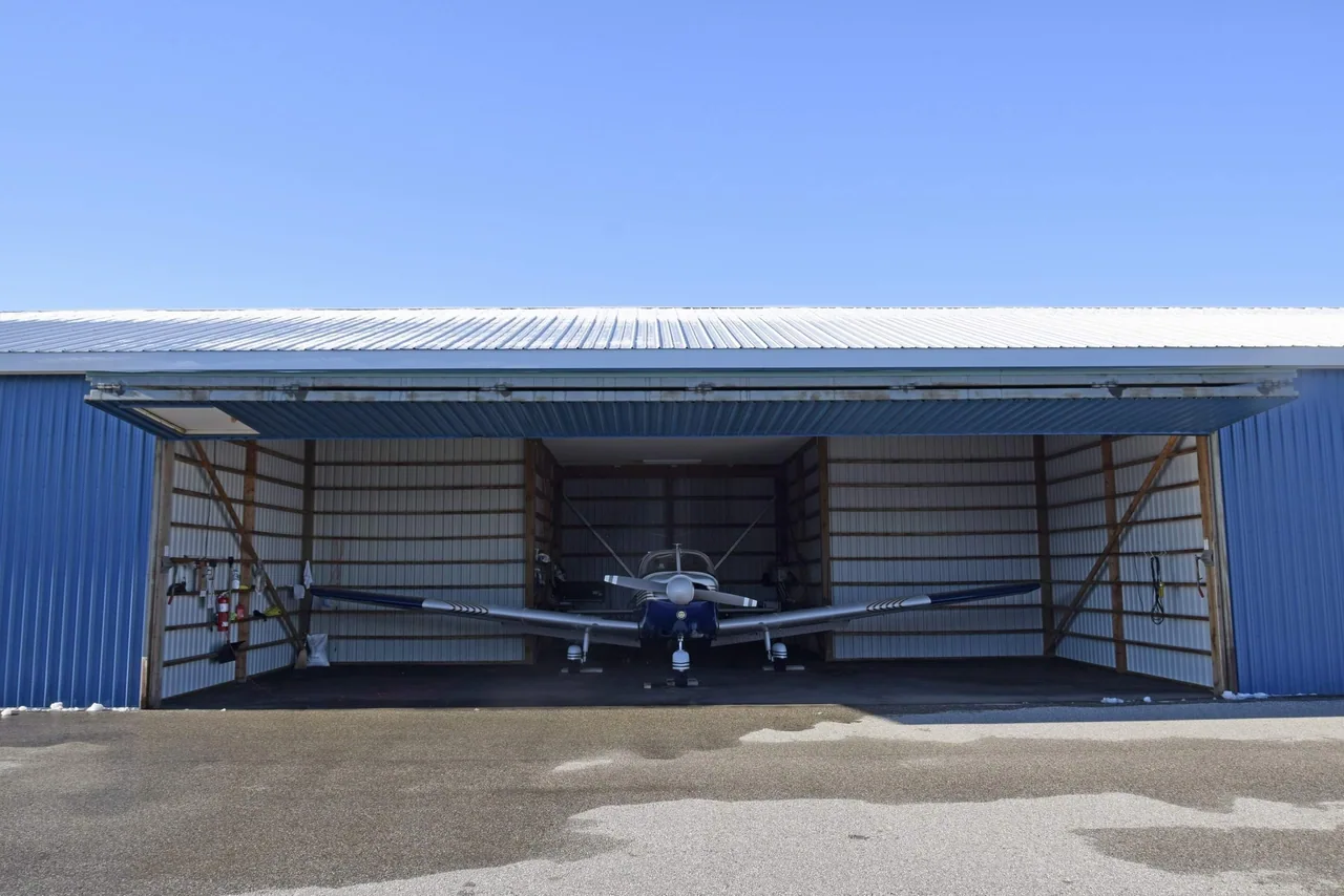 A propeller airplane parked inside an open aircraft hangar