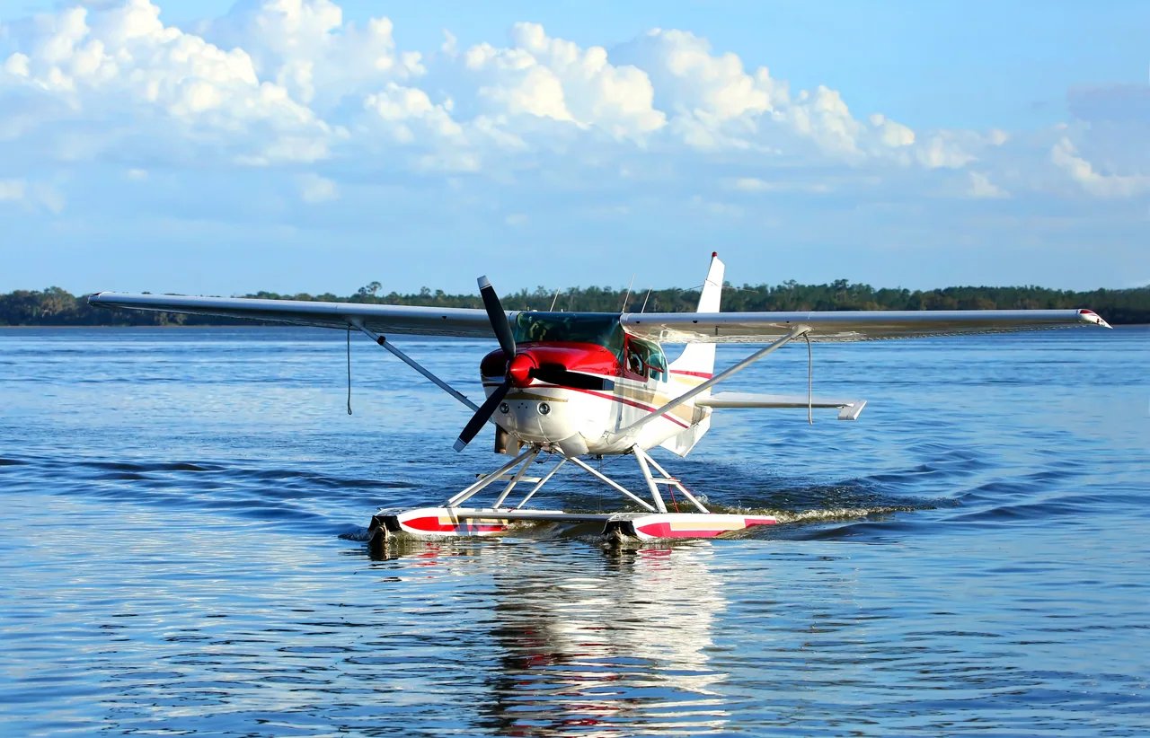 A red and white floatplane taxiing on a lake