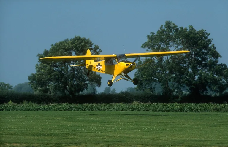 Piper PA-18 Super Cub taking off from a grass airfield