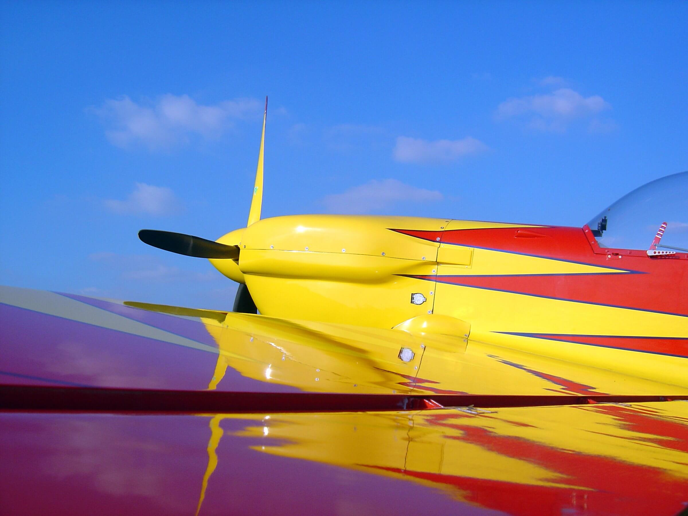 Close view of a yellow airplane nose and propeller