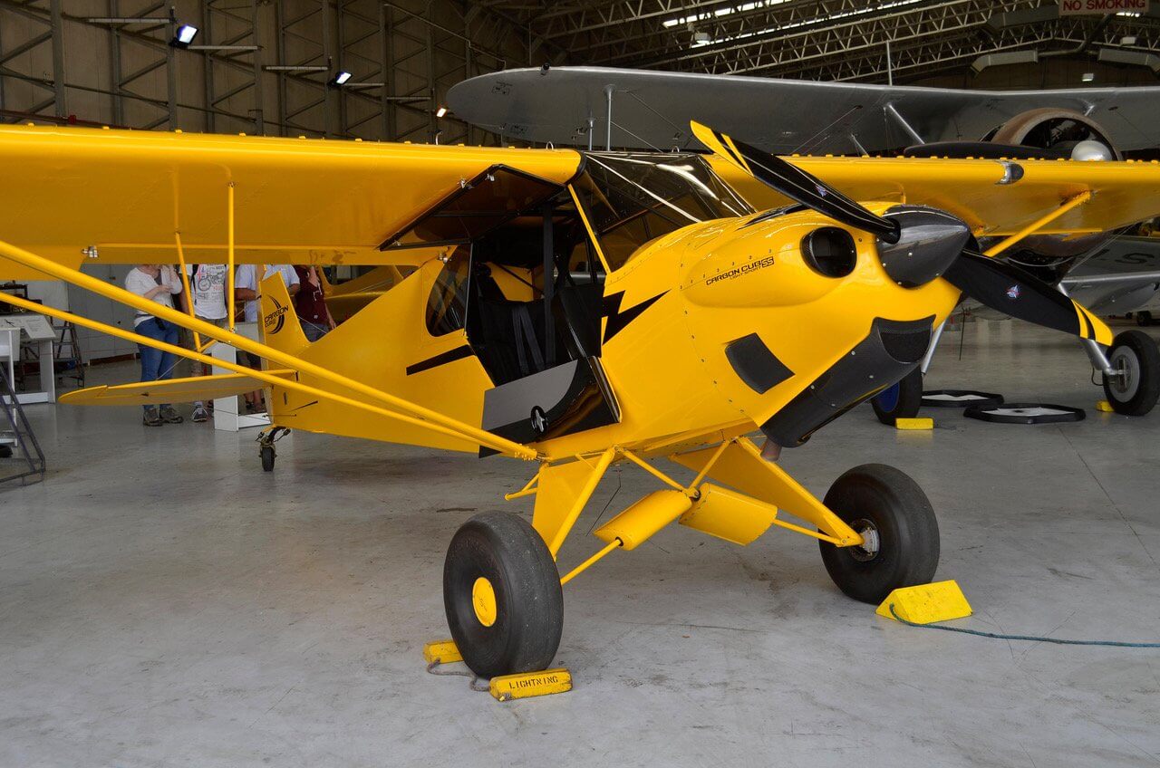 Yellow tailwheel airplane inside a hangar