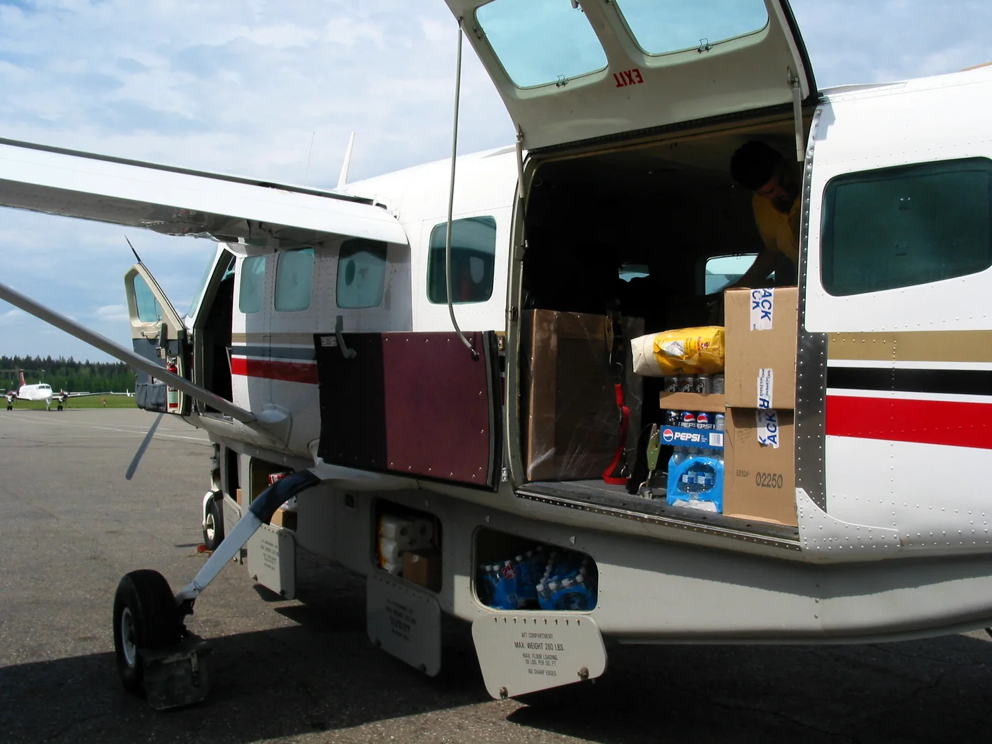 Boxes and supplies visible through the open side door of a light aircraft