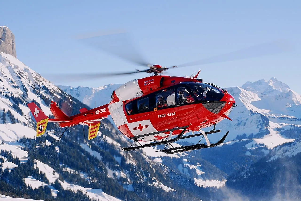 Rega BK 117 C2 EC145 rescue helicopter in flight above Swiss mountains