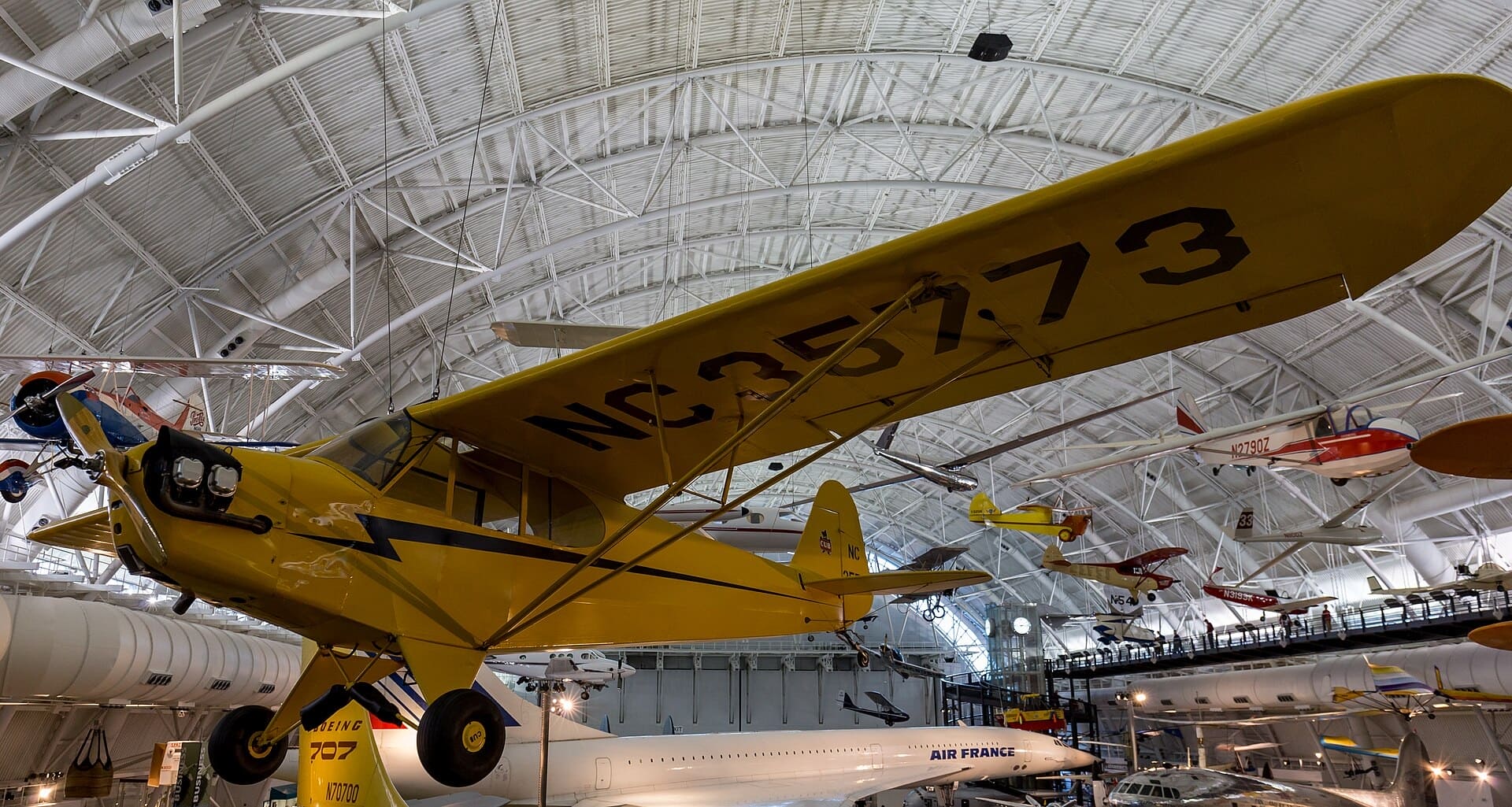 Yellow Piper J3 Cub suspended in a museum aircraft display
