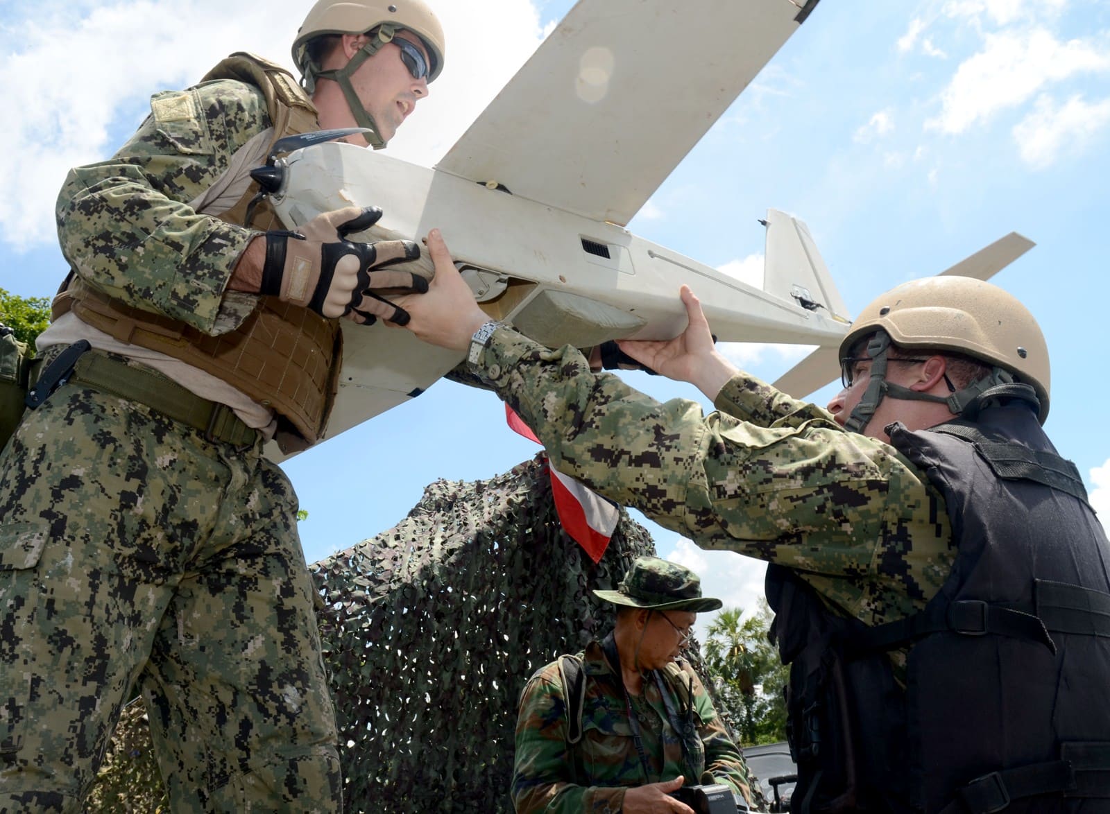 U.S. Navy personnel moving a fixed-wing unmanned aircraft between a pier and riverine boat in Thailand in 2013