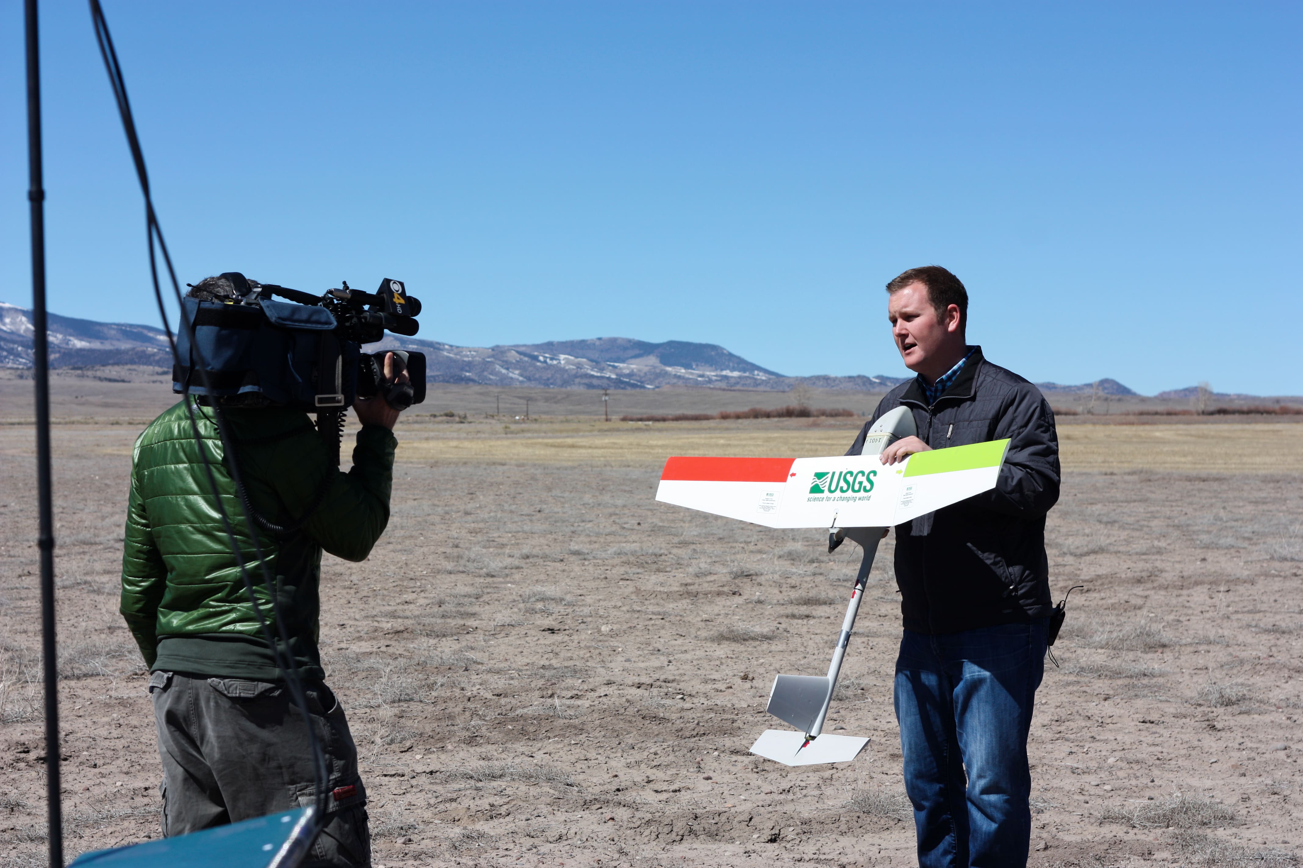 Presenter holding a small fixed-wing USGS unmanned aircraft during a migratory-bird survey demonstration