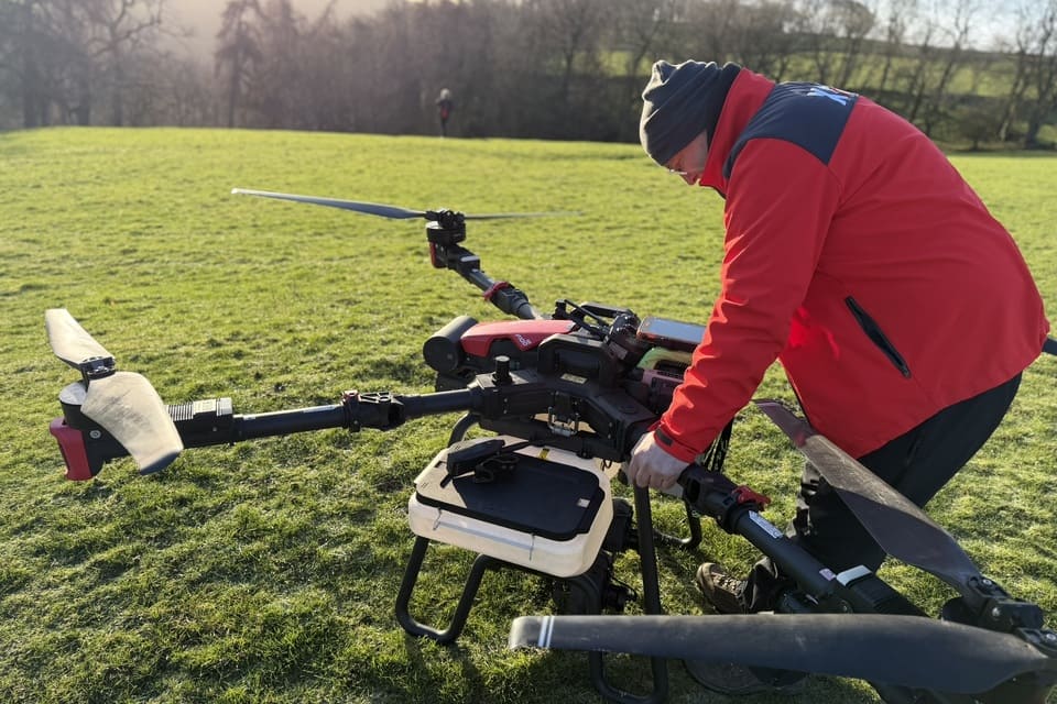 Person beside a dispensing drone in the Natural England ravine-woodland seeding trial