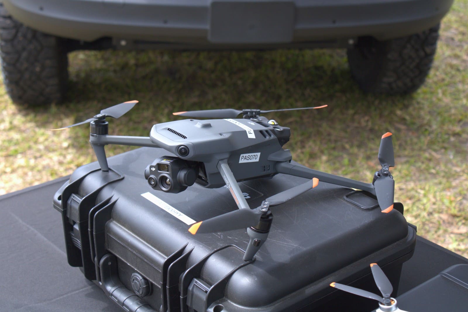 Gray quadcopter with multiple camera lenses resting on a black equipment case