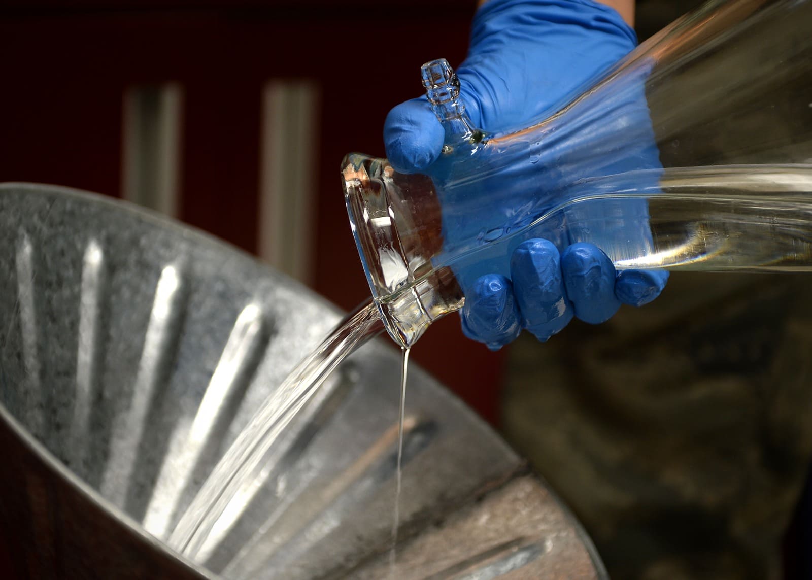 Gloved hands pouring fuel from laboratory glassware