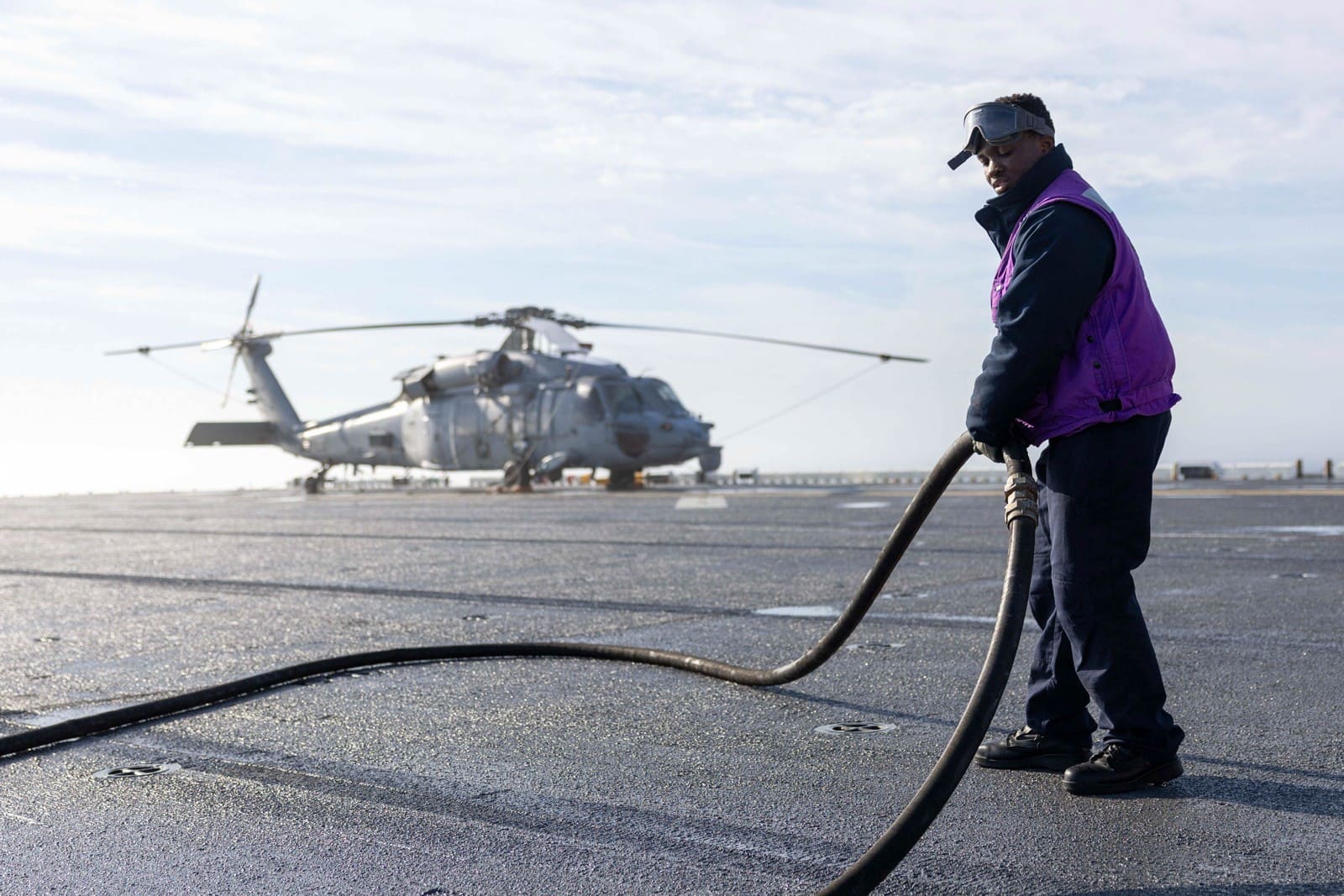 US Navy sailor carrying a fuel hose in 2025