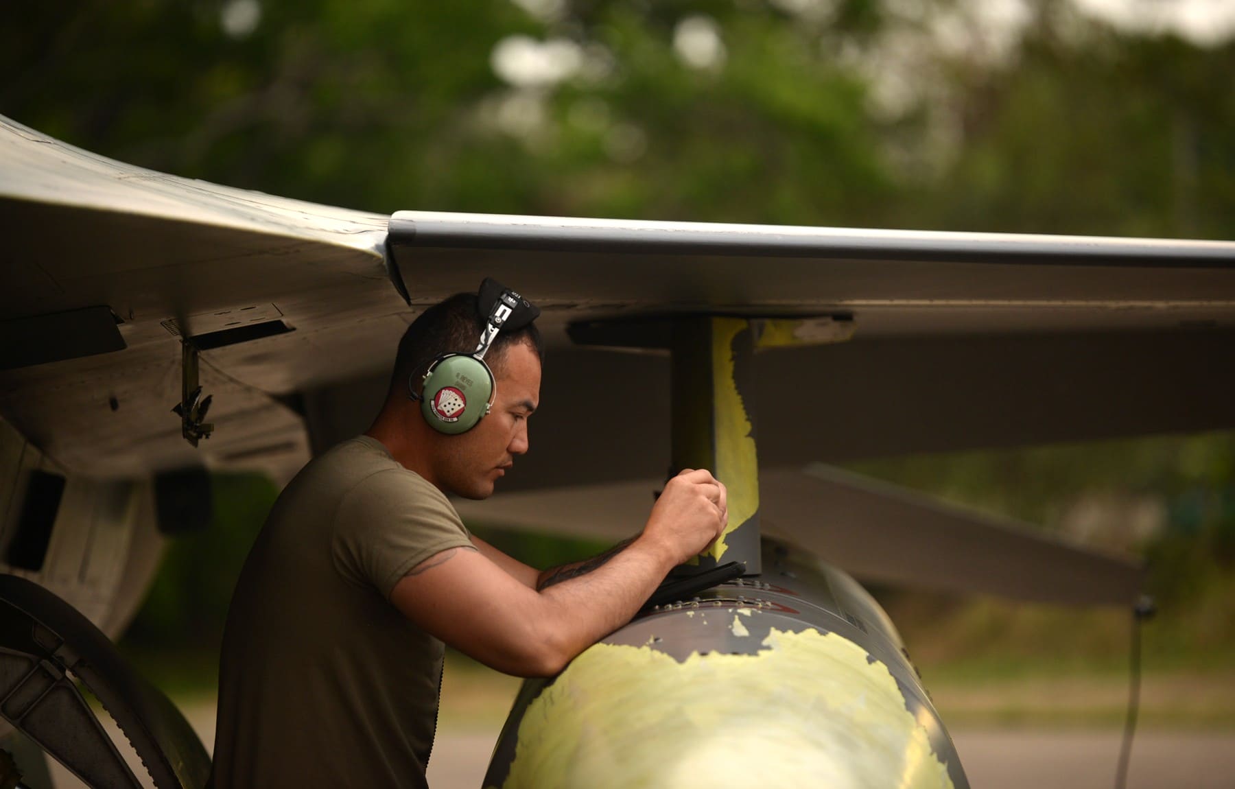 Air Force crew chief reviewing aircraft technical information on a tablet beneath an aircraft wing