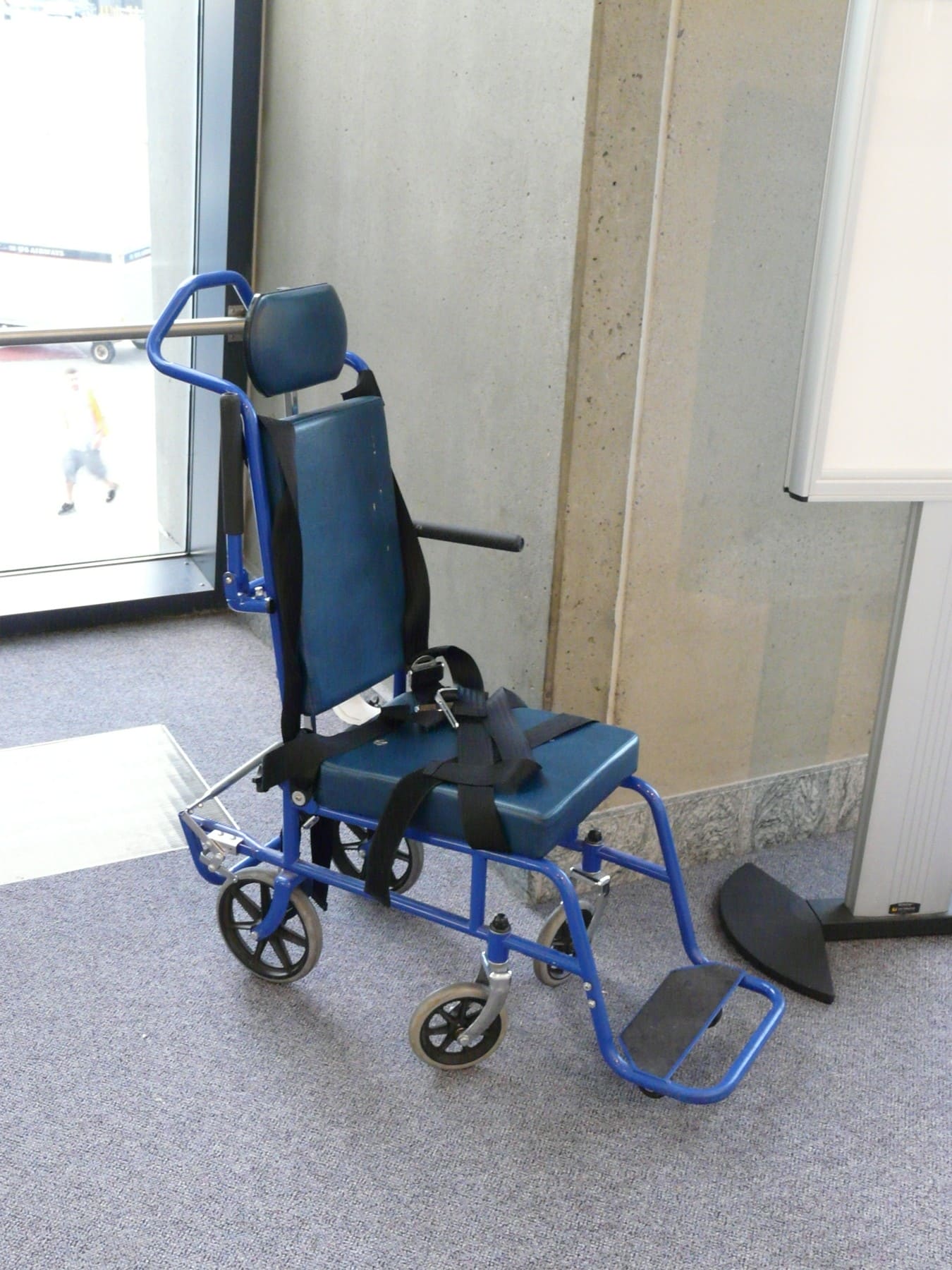 Unoccupied blue airport transport wheelchair in Boston in 2008