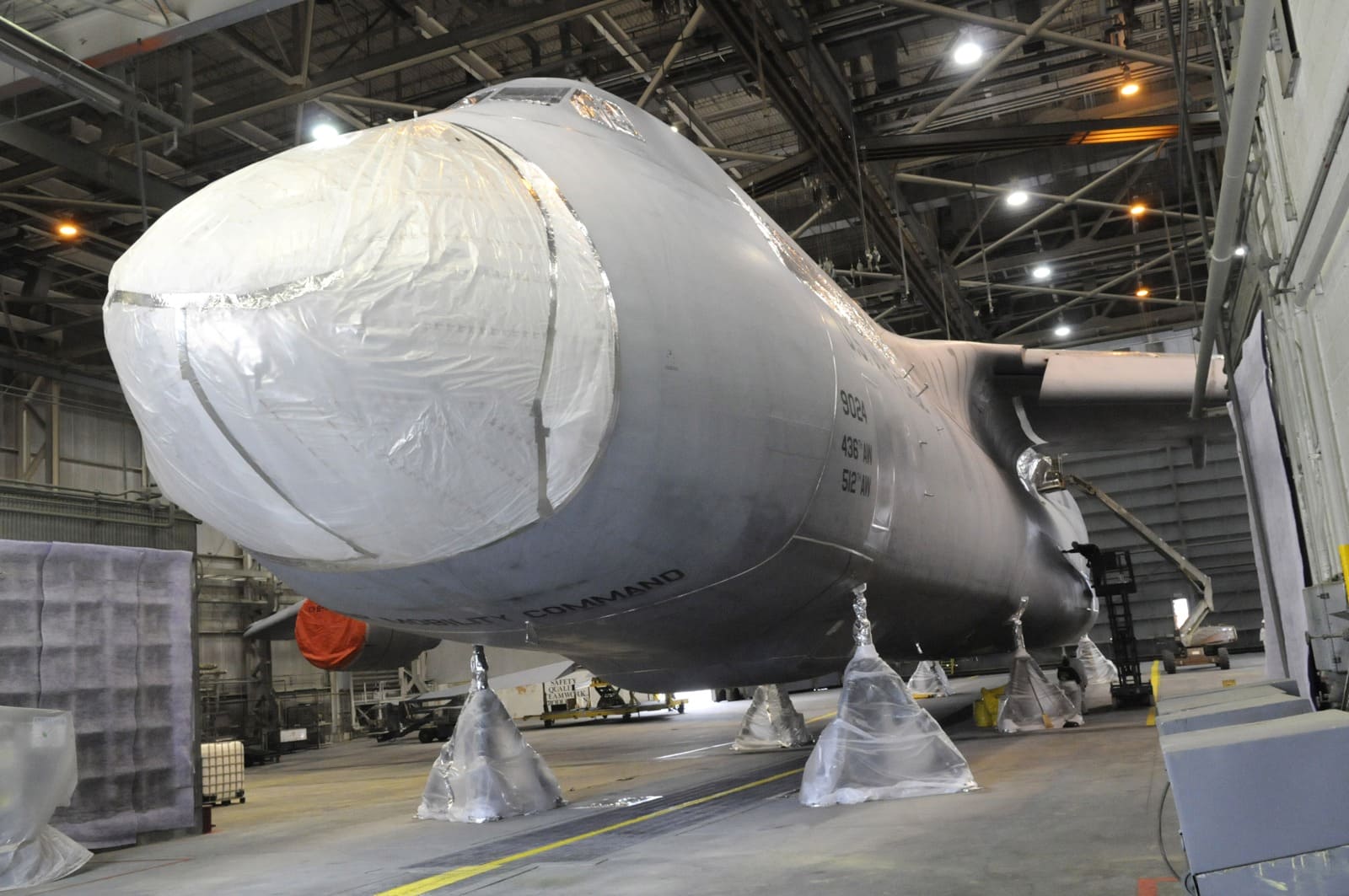 A masked military transport aircraft inside a hangar