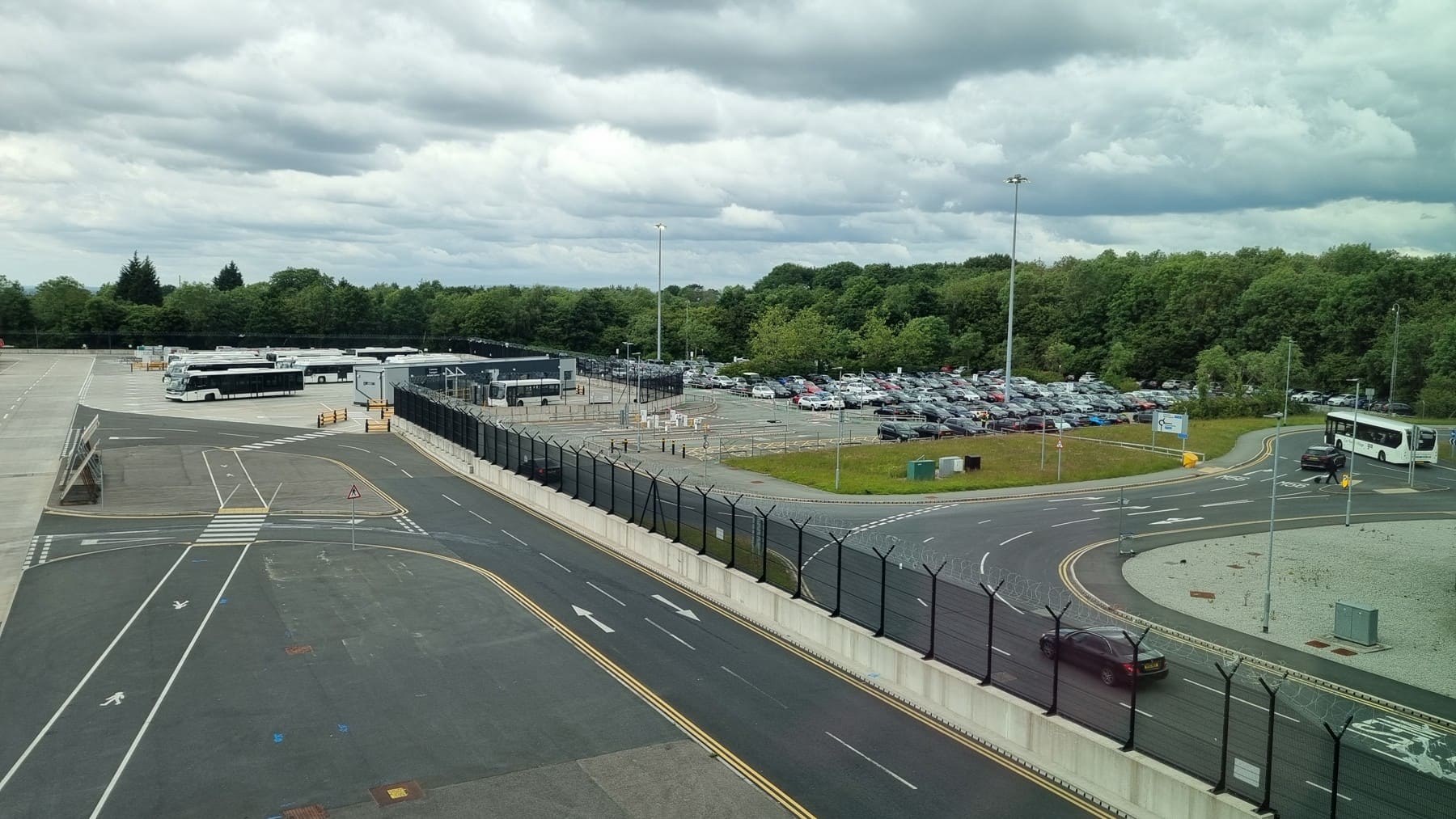 Airport fence beside roads and bus parking at Manchester Airport in June 2024
