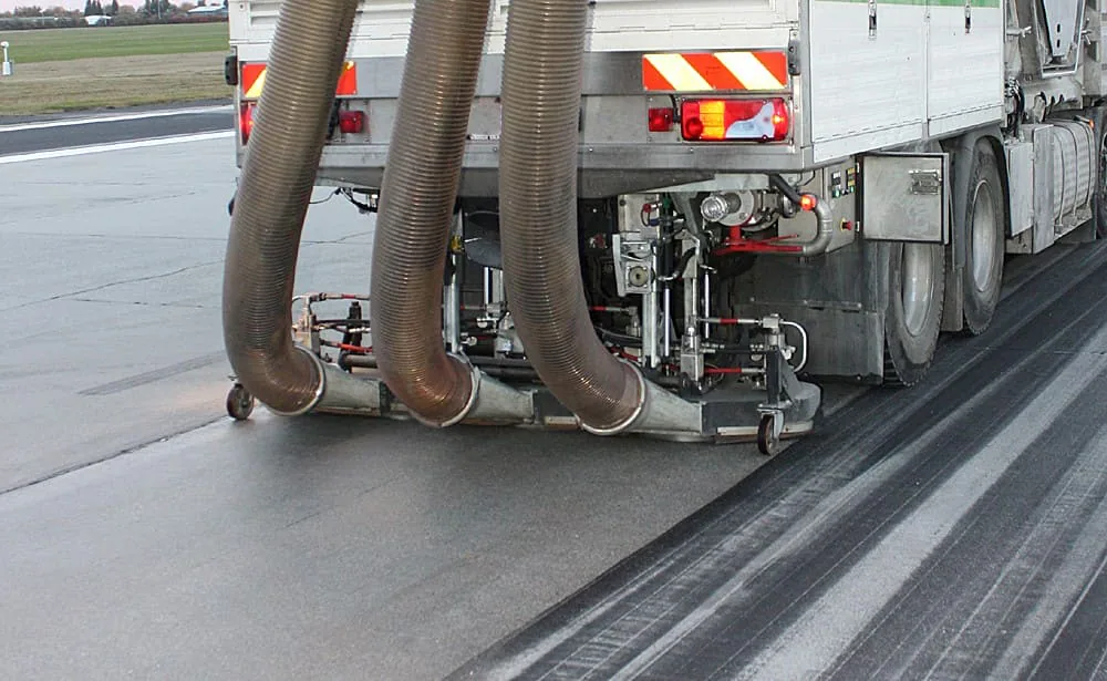 Historical runway cleaning vehicle with hoses and cleaning equipment beside rubber deposits