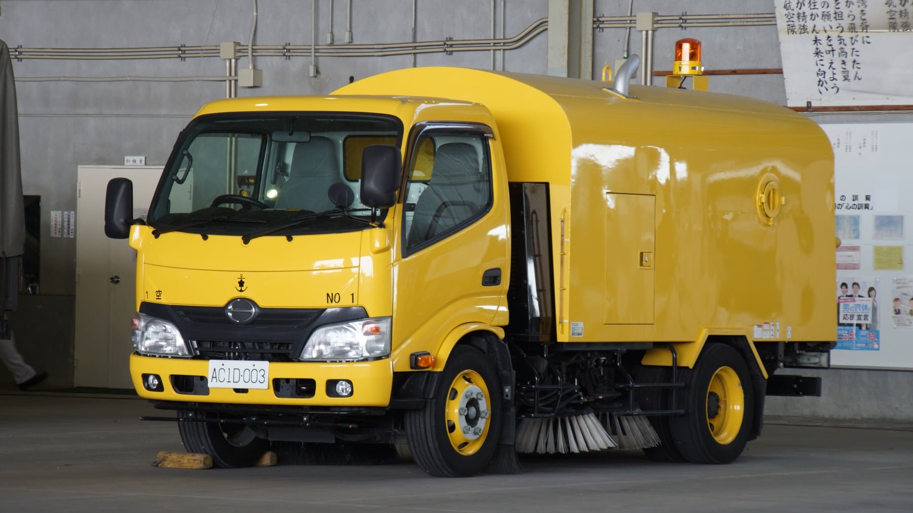 Yellow Japan Maritime Self Defense Force runway sweeper parked at Kanoya Air Base in April 2017