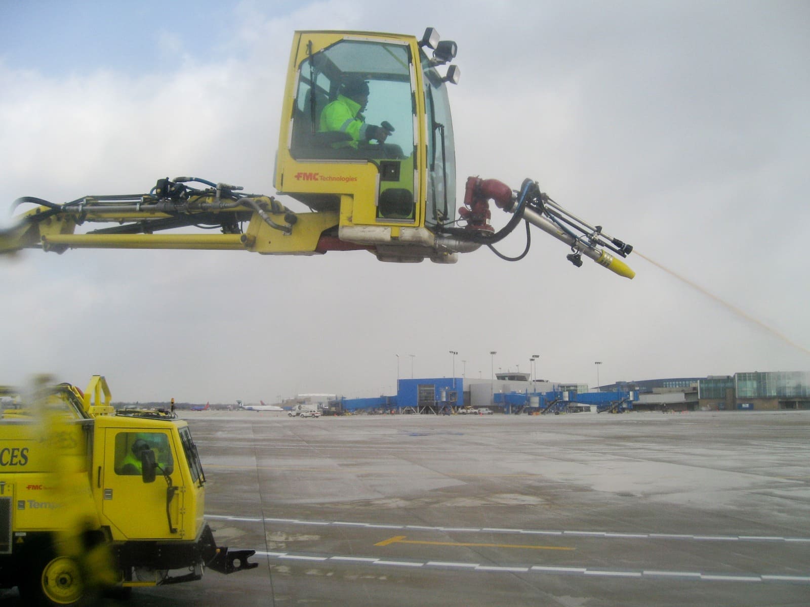 Operator in an elevated enclosed deicing truck basket with spraying nozzle